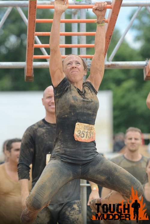 challenge yourself with the Tough Mudder like this girl crossing monkey bars